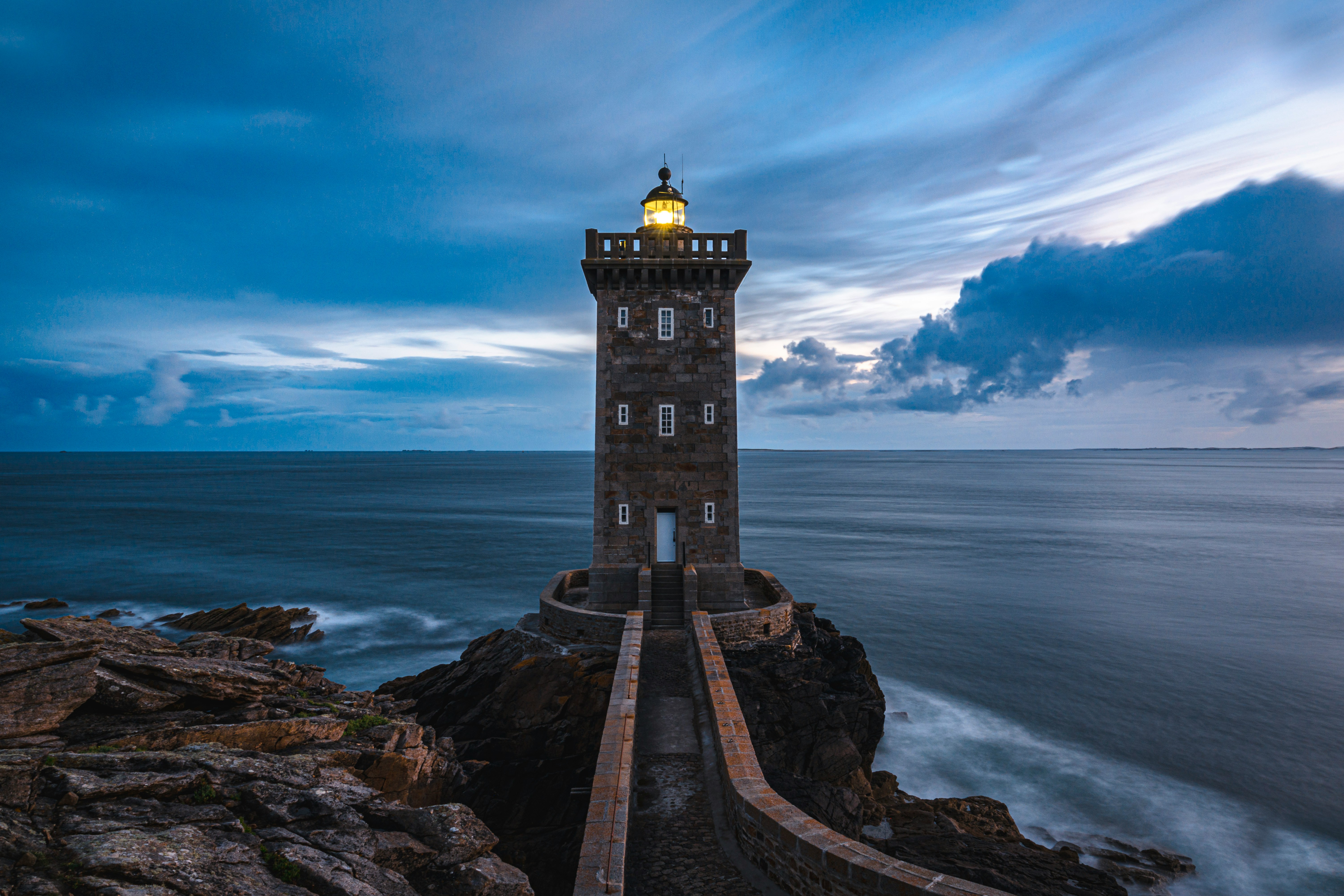 A stone lighthouse on a rocky point at blue hour